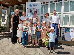 Gruppenbild der Kita-Leitung Gänseblümchen mit Kita-Kindern und der Auszeichnung zur KlimaKita.NRW.