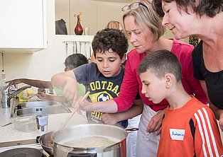 Zwei erwachsene Personen und zwei Kinder kochen gemeinsam